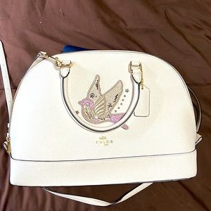 Coach woman’s purse with purple and tan bird.